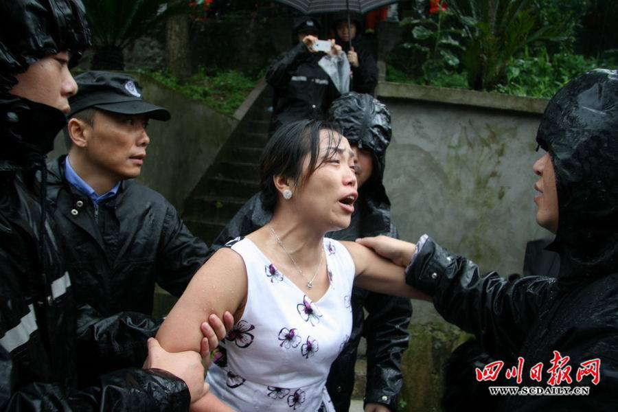 Rescuers discourage a woman from going back to flood-hit village. Rain-triggered mountain torrents and landslides buried 11 households, leaving two people dead and 21 missing. As of 9:45 p.m., 352 people stranded have been relocated to safe areas. (Photo by Luo Xiangming /scdaily.cn)