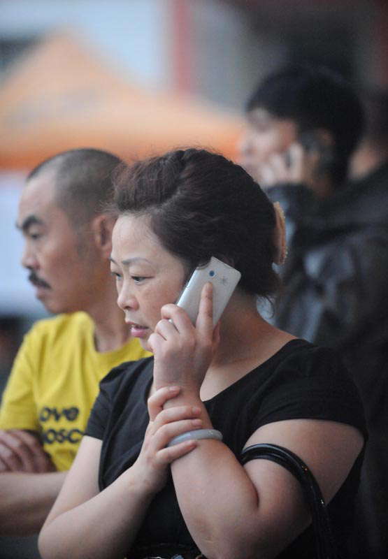 A woman uses cell phone to connect with her family in a temporary settlement site for people rescued in flood-hit Zhongxing county in southwest China's Sichuan province. Rain-triggered mountain torrents and landslides buried 11 households, leaving two people dead and 21 missing. As of 9:45 p.m., 352 people stranded have been relocated to safe areas. (Xinhua/ Xue Yubin)