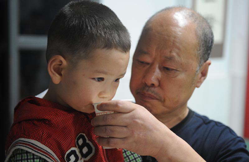 A senior man helps a child drink water in a temporary settlement site for people rescued in flood-hit Zhongxing county in southwest China's Sichuan province. Rain-triggered mountain torrents and landslides buried 11 households, leaving two people dead and 21 missing. As of 9:45 p.m., 352 people stranded have been relocated to safe areas. (Xinhua/Xue Yubin)
