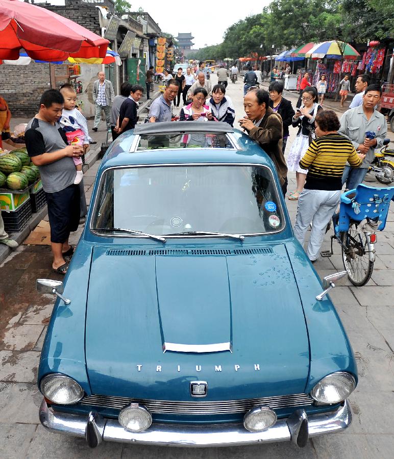 Local people view a Triumph 1300 made in 1967 in Pingyao, north China's Shanxi Province, July 10, 2013. [Photo: Xinhua] 