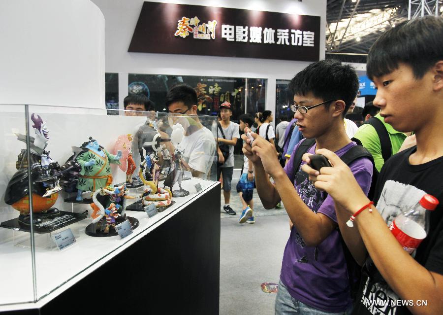 Visitors take photos of models of cartoon characters at the 9th China International Comics Games Expo (CCG Expo) in Shanghai, east China, July 11, 2013. A total of 325 animation and game companies from at home and abroad took part in the five-day expo, which kicked off here on Thursday. (Xinhua/Ding Ting)  