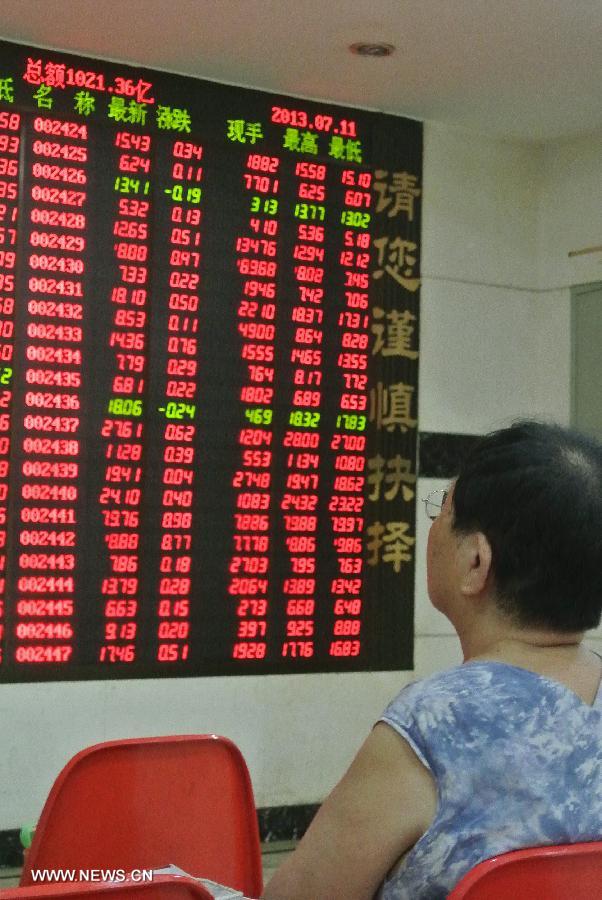 An investor looks at a screen showing stock information at a trading hall of a securities firm in Beijing, capital of China, July 11, 2013. Chinese shares jumped to a three-week high Thursday over media reports that financing rules may be partially relaxed for real estate firms. The benchmark Shanghai Composite Index jumped 3.23 percent, or 64.86points, to end at 2,072.99. The Shenzhen Component Index soared 4.25 percent, or 333.52 points, to 8,184.77. (Xinhua/Li Xin)