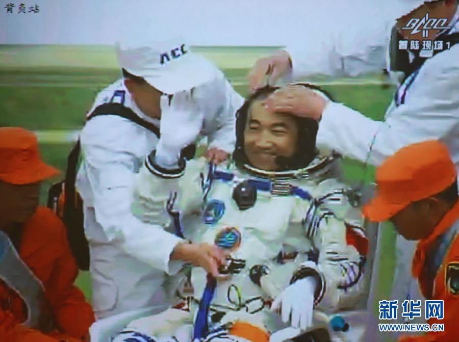 Astronaut Zhang Xiaoguang waves to people after going out of the re-entry capsule of China's Shenzhou-10 spacecraft on June 26, 2013. (Xinhua)