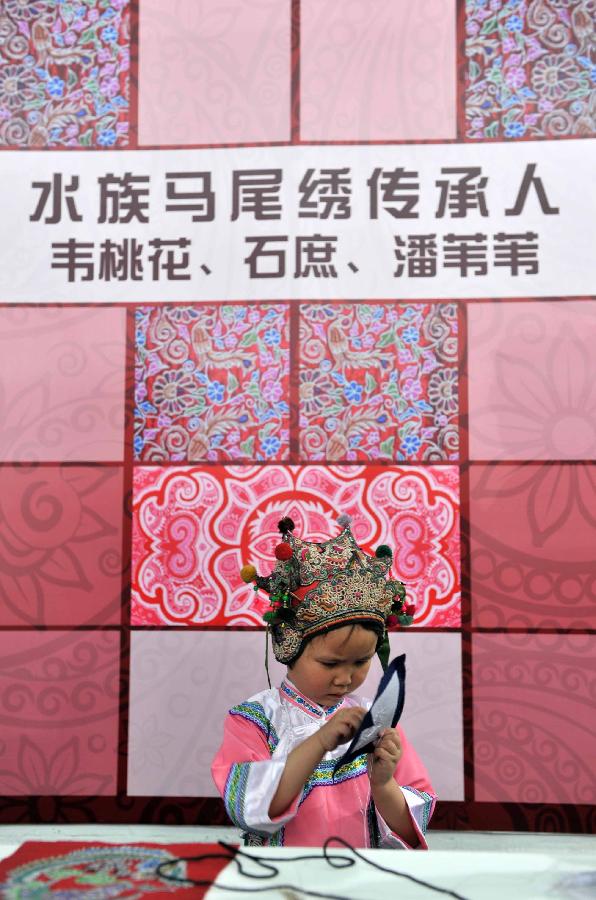 Pan Weiwei, a five-year-old inheritor of horsetail embroidery of the Shui ethnic group, shows skills during a folk handicraft exhibition in Beijing, capital of China, July 11, 2013. The five-day exhibition, opened on Thursday, displayed folk handicrafts made in southwest China's Guizhou Province. (Xinhua/Li Wen) 