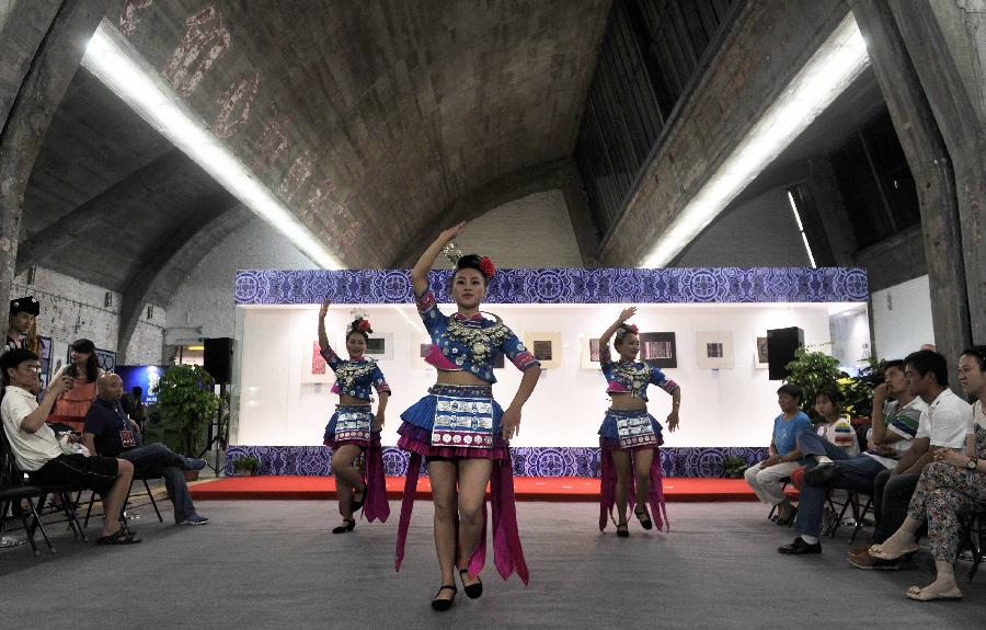 Visitors enjoy folk dance during a folk handicraft exhibition in Beijing, capital of China, July 11, 2013. The five-day exhibition, opened on Thursday, displayed folk handicrafts made in southwest China's Guizhou Province. (Xinhua/Li Wen)