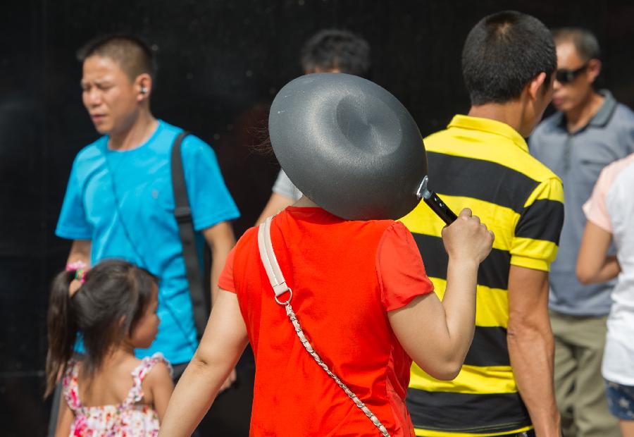 People walk on Guangyinqiao walking street during a heat wave in Chongqing, southwest China's municipality, July 11, 2013. Local meteorological observatory issued an orange-coded alert of heat on Thursday, as temperature in some parts of Chongqing has risen up to 37 degrees Celsius. (Xinhua/Chen Cheng)