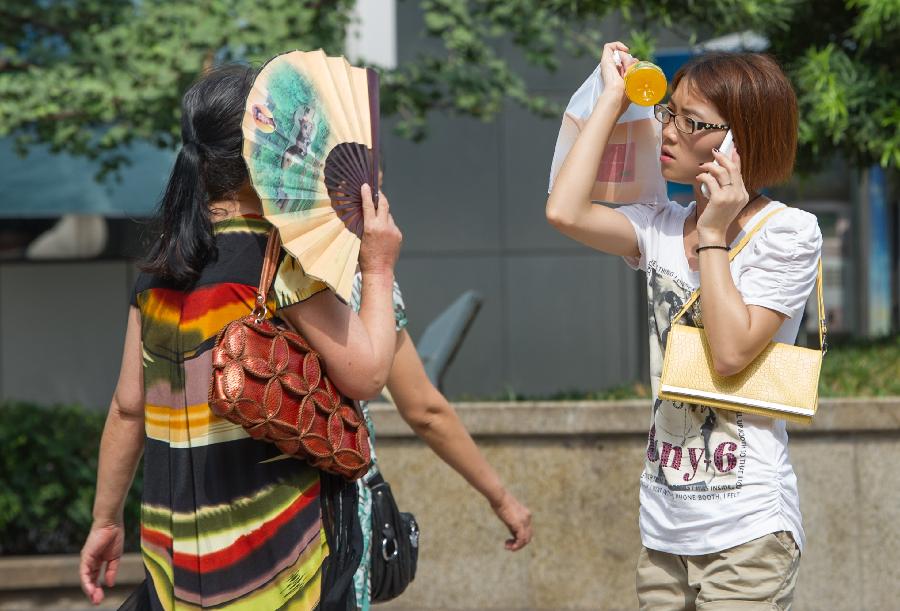 Women walk on Guangyinqiao walking street during a heat wave in Chongqing, southwest China's municipality, July 11, 2013. Local meteorological observatory issued an orange-coded alert of heat on Thursday, as temperature in some parts of Chongqing has risen up to 37 degrees Celsius. (Xinhua/Chen Cheng)
