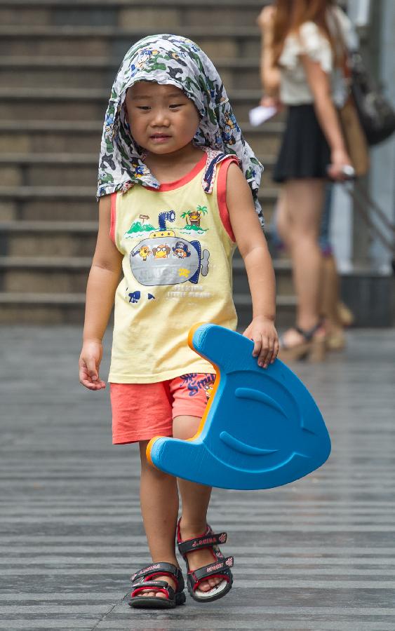 A little boy walks on Guangyinqiao walking street during a heat wave in Chongqing, southwest China's municipality, July 11, 2013. Local meteorological observatory issued an orange-coded alert of heat on Thursday, as temperature in some parts of Chongqing has risen up to 37 degrees Celsius. (Xinhua/Chen Cheng)