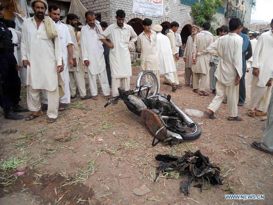 Residents gather around a destroyed motorbike at the blast site in northwest Pakistan's Kohat, July 11, 2013. At least three people were killed and 10 others injured when a bomb went off outside a mosque in Pakistan's northwest Kohat district on Thursday afternoon, local Urdu media reported. (Xinhua/Stringer)