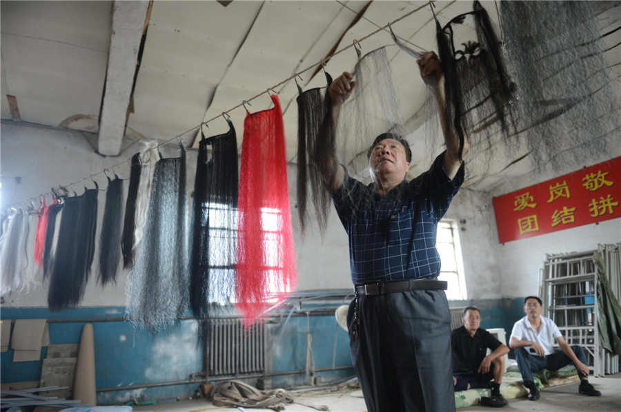 Liu Zongfa, inheritor of Haha Tune and head of the troupe, arranges beard props in Kouzhuang village, Mumendian town, Qing county, Hebei province, July 10, 2013. (Xinhua)