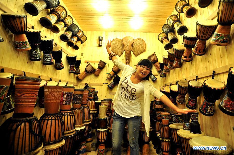 Shi Wenli, a 20-year-old owner of the djembe shop, poses for photos in Pingyao County, north China's Shanxi Province, July 10, 2013. No matter whether they are natives, migrators or tourists, they have their own stories in this ancient town. (Xinghua/He Canling)