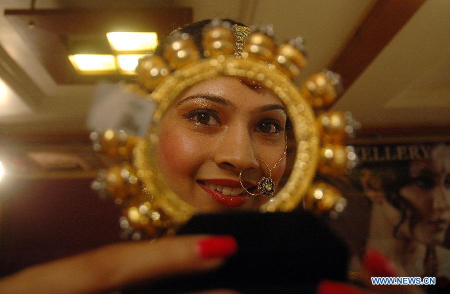 A model's face is reflected on a displayed jewelry of ancient temples of India during the exhibition "Temple Collection" in Bhopal, India, July 11, 2013. (Xinhua/Stringer) 