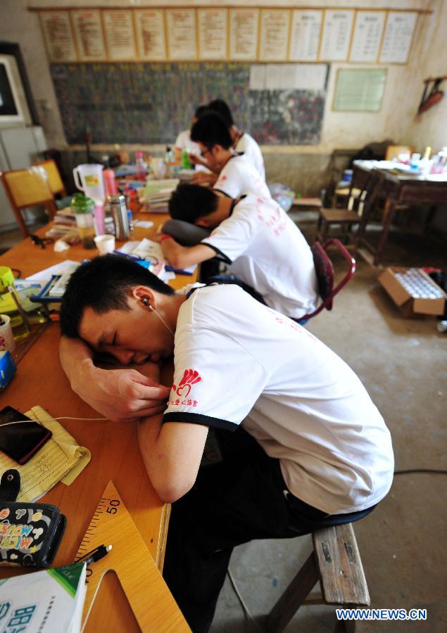 Volunteers have a nap at Maolong Primary School of Wangdun Township in Duchang County, east China's Jiangxi Province, July 11, 2013. Twenty-four student volunteers of the Wuchang Branch of Huazhong University of Science and Technology came to the primary school to carry out 20-day education support activities for about 200 left-behind children in the summer vacation. (Xinhua/Hu Guolin)
