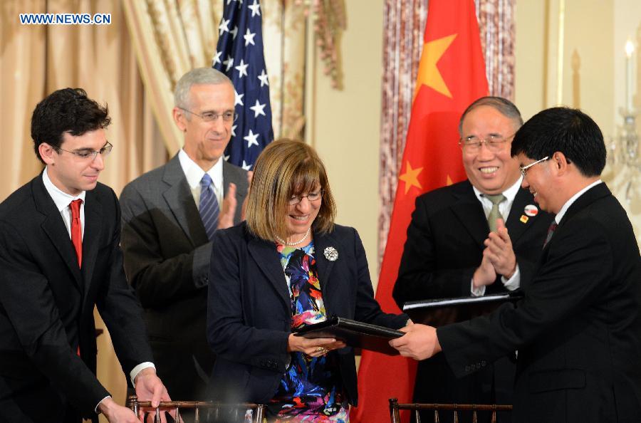 Representatives of enterprisers from China and the United States exchange agreements at a signing ceremony of China-U.S. EcoPartnership program in Washington, the United States, July 11, 2013. China and the United Sates on Thursday expanded their EcoPartnership program with the signing of six new partnerships to reduce greenhouse gases emissions and improve energy efficiency as well as to create jobs. (Xinhua/Wang Lei)