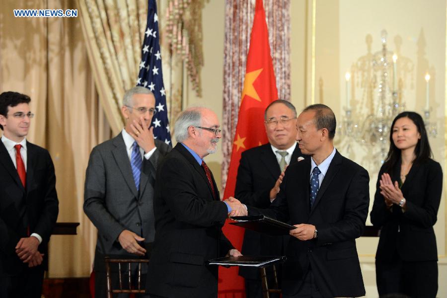 Representatives of enterprisers from China and the United States exchange agreements at a signing ceremony of China-U.S. EcoPartnership program in Washington, the United States, July 11, 2013. China and the United Sates on Thursday expanded their EcoPartnership program with the signing of six new partnerships to reduce greenhouse gases emissions and improve energy efficiency as well as to create jobs. (Xinhua/Wang Lei)