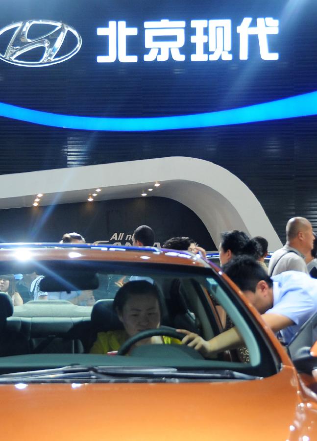 A visitor experiences a Hyundai vehicle at the 10th China Changchun International Automobile Expo in Changchun, capital of northeast China's Jilin Province, July 12, 2013. A total of 146 auto brands from 127 companies took part in the ten-day expo, which kicked off here on Friday. (Xinhua/Lin Hong)