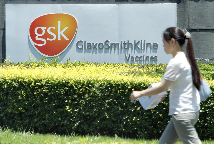 A pedestrian walks outside a vaccines company of GlaxoSmithKline (GSK), Britain's biggest drug maker, in Shanghai, east China, July 12, 2013. Some senior executives from GlaxoSmithKline(China) Investment Co., Ltd are being investigated for suspected bribery and tax-related violations, Chinese police said Thursday. (Xinhua/Ding Ting)