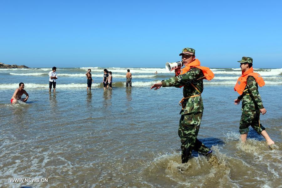 Officers persuade visitors who swim in the sea to go ashore at a bathing beach in Changle, southeast China's Fujian Province, July 12, 2013. Typhoon Soulik is expected to hit or pass waters near southeast China's Taiwan late Friday or early Saturday morning before landing on the mainland on Saturday, according to the National Marine Environmental Forecasting Center. (Xinhua/Zhang Guojun)