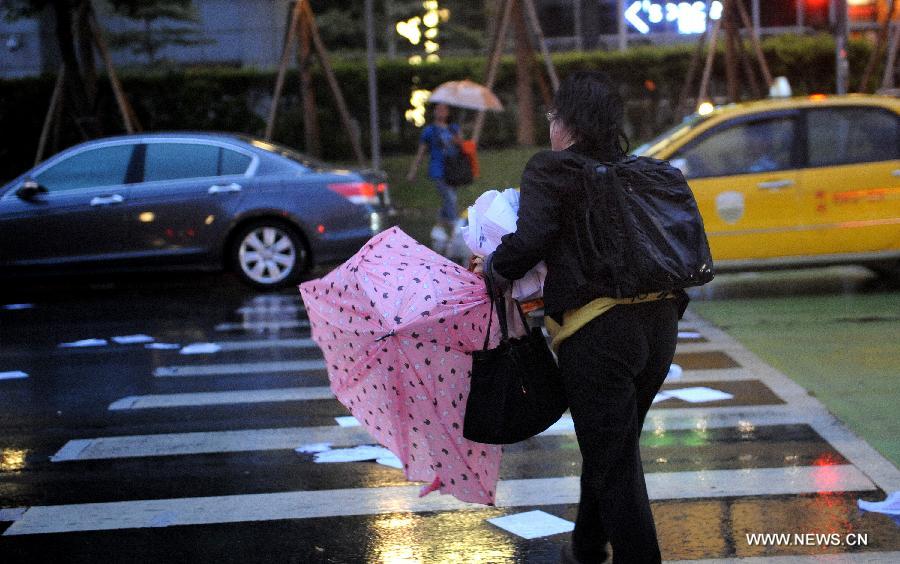 A citizen walks against rain and wind in Taipei, southeast China's Taiwan, July 12, 2013. Typhoon Soulik is expected to hit or pass waters near Taiwan late Friday or early Saturday morning before landing on the mainland on Saturday, according to the National Marine Environmental Forecasting Center. (Xinhua/Tao Ming) 