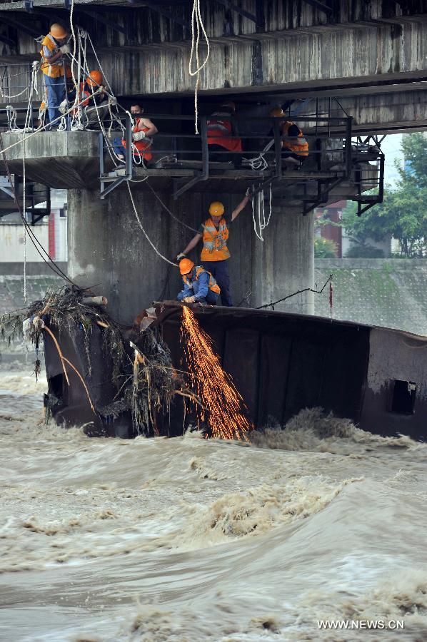 Rescue workers cut apart the iron barge stuck at a pier of the Qingbaijiang Bridge of the Baocheng Railway in Chengdu, capital of southwest China's Sichuan Province, July 12, 2013. Affected by the rain-triggered floods, an iron barge hit the Qingbaijiang Bridge on July 9, causing damages to some sections of the bridge. (Xinhua/Wang Zhengwei) 