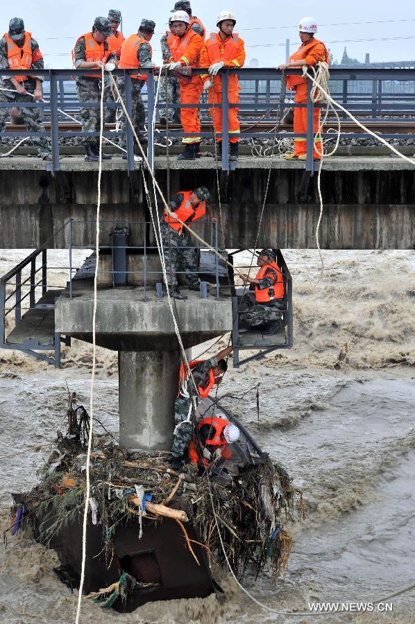 Rescue workers clean up the rubbish on the iron barge stuck at a pier of the Qingbaijiang Bridge of the Baocheng Railway in Chengdu, capital of southwest China's Sichuan Province, July 12, 2013. Affected by the rain-triggered floods, an iron barge hit the Qingbaijiang Bridge on July 9, causing damages to some sections of the bridge. (Xinhua/Wang Zhengwei) 