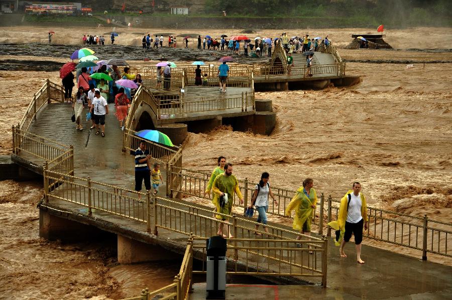 Tourists view the Hukou Waterfall of the Yellow River from the site in Jixian County, north China's Shanxi Province, July 12, 2013. Triggered by non-stop heavy rainfall in the upper reaches, the rising water level of the Yellow River surged the Hukou Waterfall, attracting many visitors. (Xinhua/Lu Guiming) 