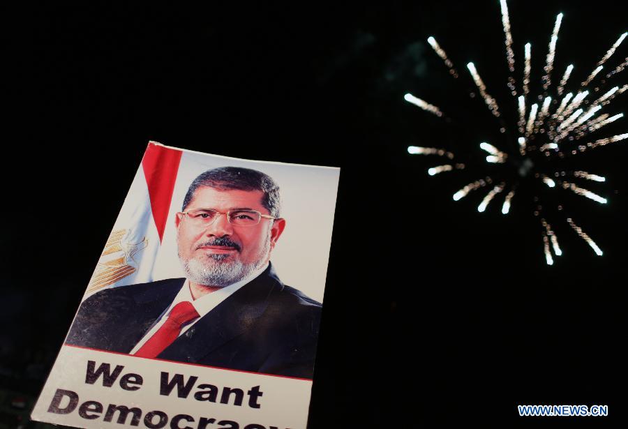 Fireworks explode above a poster of ousted president Mohamed Morsi during a pro-Morsi protest near the Rabaa al-Adawiya mosque, in Cairo, Egypt, July 12, 2013. (Xinhua/Wissam Nassar) 