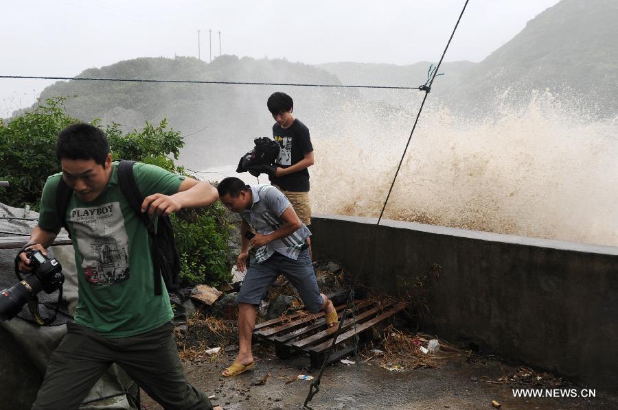 Journalists hide away from the big waves brought by the strong wind along a sea dike in Cangnan County, east China's Zhejiang Province, July 13, 2013. Typhoon Soulik is expected to make a landfall in Fujian and Zhejiang provinces on the Chinese mainland between Saturday noon and late afternoon after it passes Taiwan. (Xinhua/Ju Huanzong) 