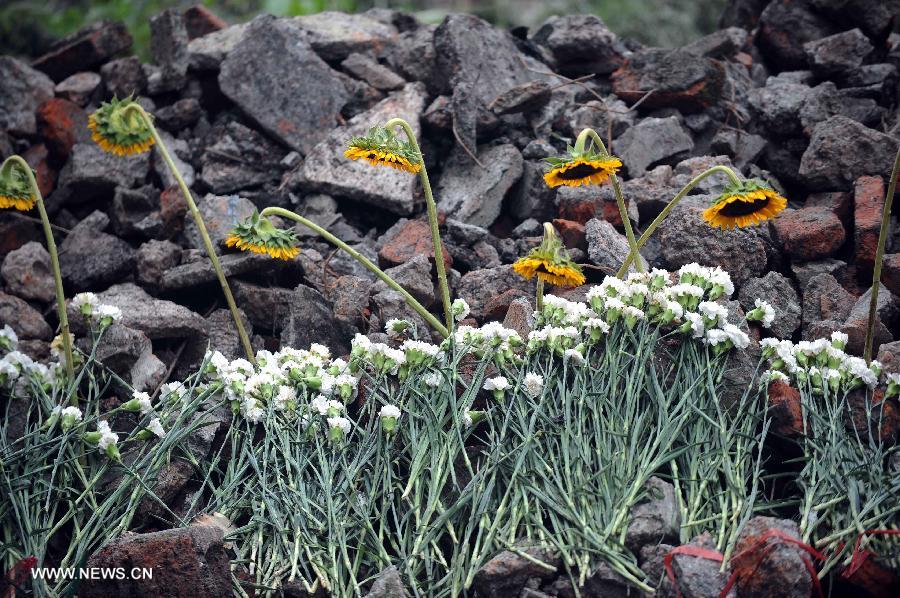 Photo taken on July 13, 2013 shows flowers presented to the victims at landslide scene in Sanxi Village of Dujiangyan City, southwest China's Sichuan Province. As of 19:00 p.m. (GMT 1100), 43 people were confirmed dead during the landslide that happened in the village of Sanxi on July 10. Some 118 people across the city were missing or can not immediately be reached. Local authorities are continuing to verify the exact number of those missing. Search and rescue work continues. (Xinhua/Xue Yubin)