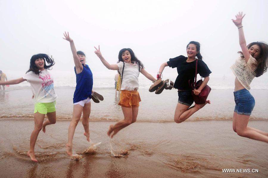 Women jump on the Jinshatan bathing beach in Qingdao, east China's Shandong Province, July 13, 2013. Saturday marks the beginning of the hottest part of summer. Many people came to the seashore to spend a cool weekend. (Xinhua/Yu Fangping)