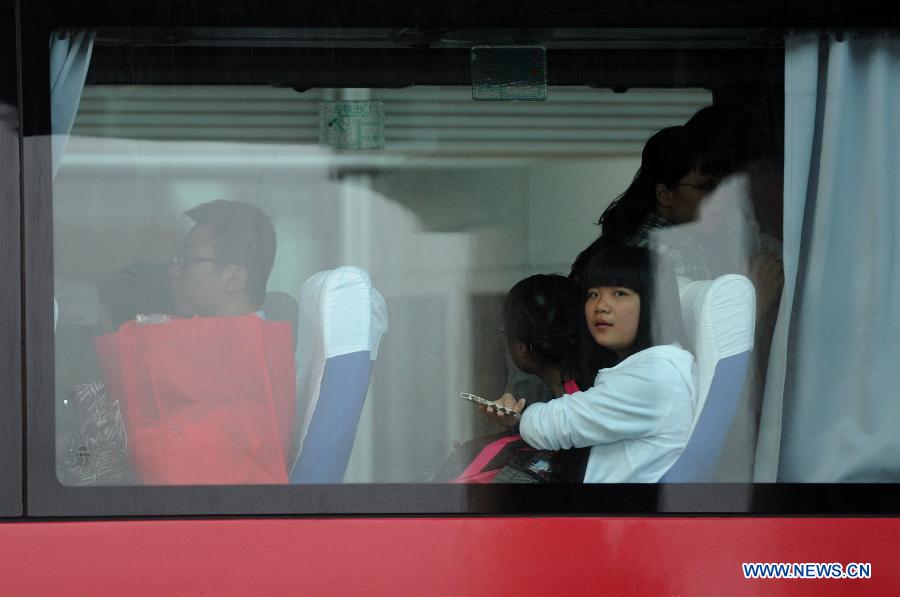 Students and teachers of Jiangshan Middle School are seen on a bus at Capital International Airport in Beijing, capital of China, July 13, 2013. A total of 31 students and teachers who were held up in the U.S. by the crash of Asiana Airlines Flight 214 at San Francisco International Airport returned to China on Saturday. Two Chinese girls were immediately killed during the crash on June 6. Another girl died on June 12 after succumbing to injuries. (Xinhua/Luo Xiaoguang)