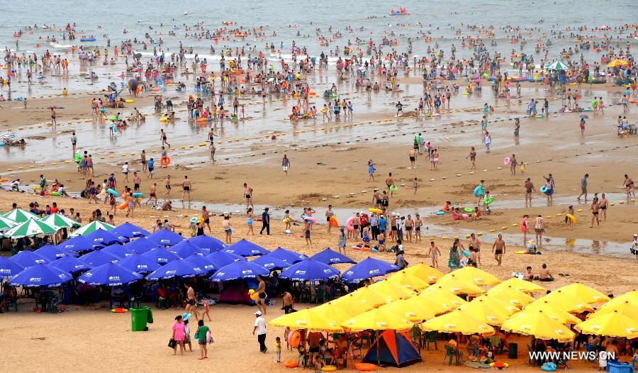 Tourists enjoy coolness at the Dashawan bathing beach in Lianyungang, east China's Jiangsu Province, July 13, 2013. Saturday marks the beginning of the hottest part of summer. Many people came to the seashore to spend a cool weekend. (Xinhua/Wang Chun)