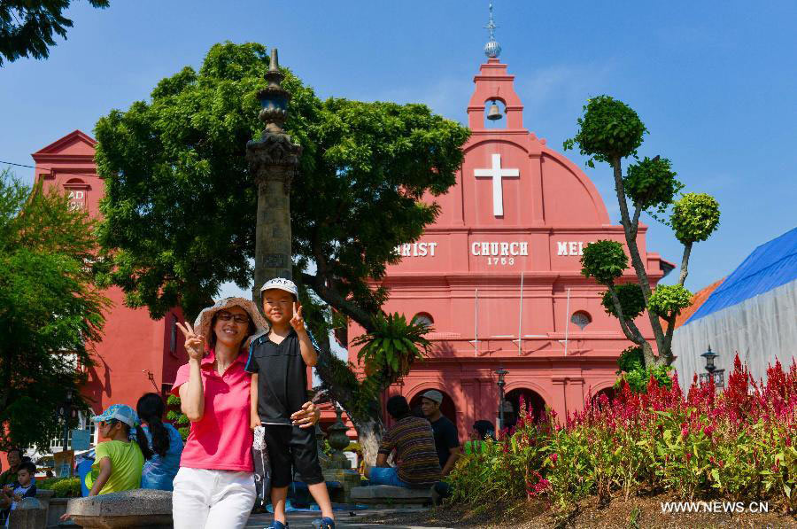 Tourists pose for a photo in front of a church which was built by Dutch in 18th century in Melaka, Malaysia, on July 12, 2013. Melaka and George Town, historic cities of the Straits of Malacca, were inscribed onto the list of UNESCO World Heritage Site in July 2008. (Xinhua/Chong Voon Chung)