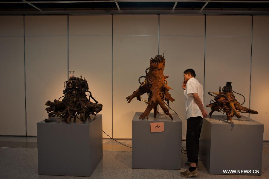 A visitor views a sculpture displayed at an exhibition of excellent sculpture works of 2013 college graduates in Beijing, capital of China, July 13, 2013. Over 100 works submitted by art academies nationwide are presented to the public from Saturday on here. (Xinhua/Zhang Cheng)