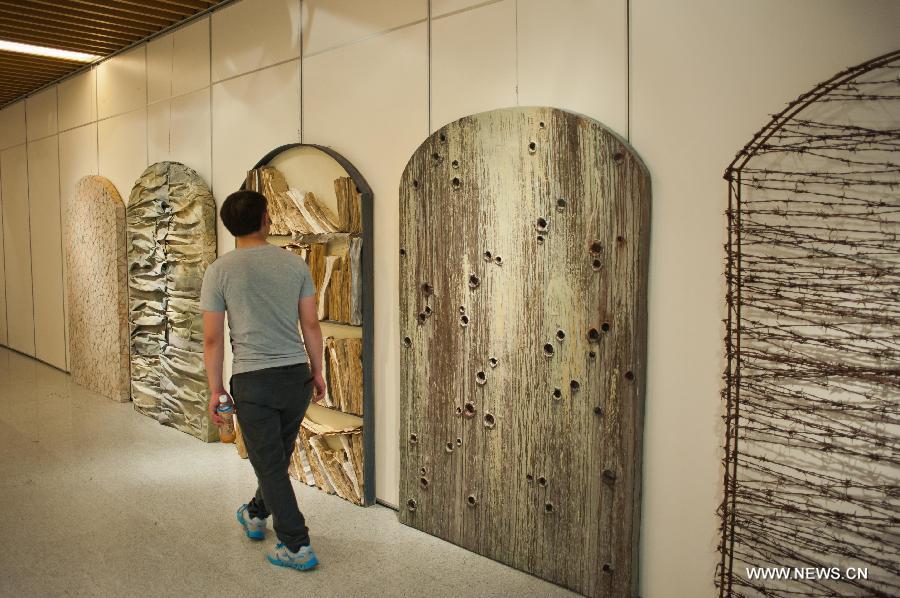 A visitor views a sculpture displayed at an exhibition of excellent sculpture works of 2013 college graduates in Beijing, capital of China, July 13, 2013. Over 100 works submitted by art academies nationwide are presented to the public from Saturday on here. (Xinhua/Zhang Cheng) 