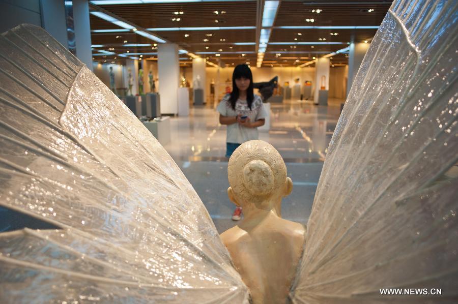 A visitor views a sculpture displayed at an exhibition of excellent sculpture works of 2013 college graduates in Beijing, capital of China, July 13, 2013. Over 100 works submitted by art academies nationwide are presented to the public from Saturday on here. (Xinhua/Zhang Cheng)