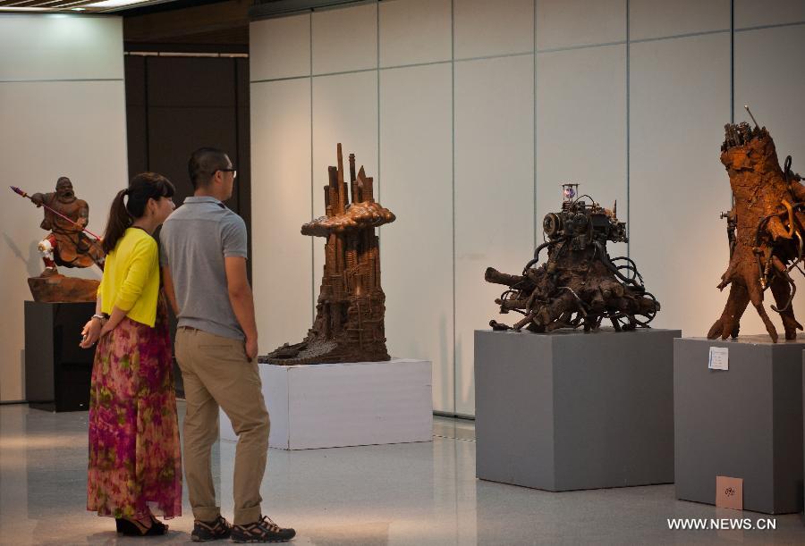 Visitors view sculptures displayed at an exhibition of excellent sculpture works of 2013 college graduates in Beijing, capital of China, July 13, 2013. Over 100 works submitted by art academies nationwide are presented to the public from Saturday on here. (Xinhua/Zhang Cheng)