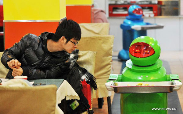 4. Robot themed restaurant , HarbinA customer watches a robot serving dishes in a robot themed restaurant in Harbin, capital of northeast China's Heilongjiang Province, Jan. 18, 2013. Opened in June of 2012, the restaurant has gained fame by using a total of 20 robots to cook meals, deliver dishes and greet customers.(Source: China.org.cn/Xinhua file photo)