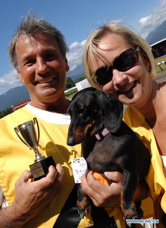 Shane Ivancoe (L) and Laurie Ivancoe hold up Doobie after the dog advanced to the finals of the annual Wiener Dog Racing at Hastings Race Course in Vancouver, Canada, July 13, 2013. More than 60 dachshunds attended the racing event held from July 13 to July 14. (Xinhua/Sergei Bachlakov) 