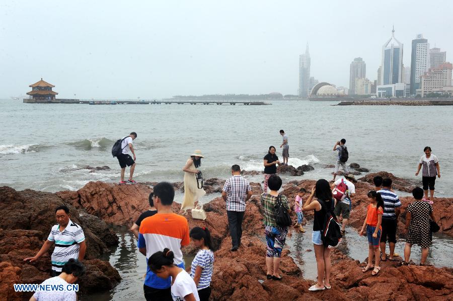 Tourists play on the reef near the Zhanqiao Bridge in Qingdao, east China's Shandong Province, July 14, 2013. A renovation work has been started to repair the Zhanqiao Bridge, a landmark for Qingdao. Part of the bridge was hit and destroyed by thunderstorms and waves on May 27. (Xinhua/Li Ziheng)  