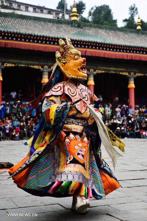 A buddhist wearing a mask attends a ceremony expressing stories of Gods and ghosts in Tibetan Buddhism at the Taer Monastery in Huangzhong County of Xining, capital of northwest China's Qinghai Province, July 14, 2013. The ceremony, which is called "Tiao Qian" in Chinese, was held on Sunday here at the monastery, the birth place of Tsongkhapa, founder of the Geluk school of Tibetan Buddhism. (Xinhua/Wu Gang)