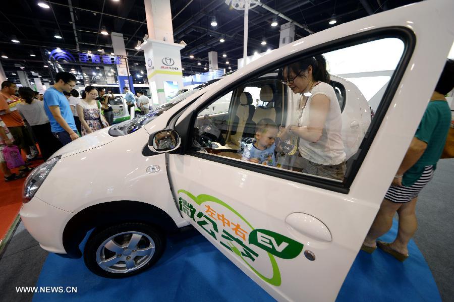 File photo taken on July 12, 2013 shows visitors trying an electric vehicle at a new energy auto exhibition in Hangzhou, capital of east China's Zhejiang Province. (Xinhua)