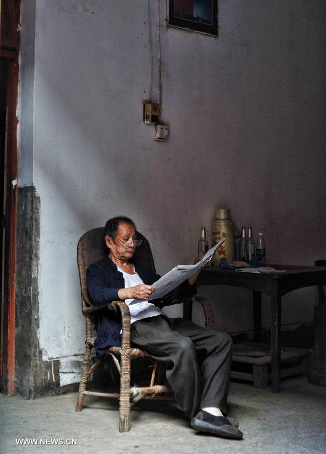 An senior citizen reads newspapers in his house in the Miao Autonomous County of Chengbu, central China's Hunan Province, July 13, 2013. An ecology tourism festival is held here from July 12 to 14. (Xinhua/Cheng Tingting) 