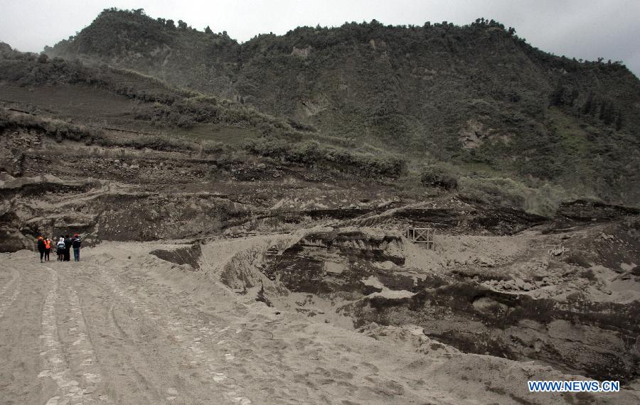 People walk on a path covered with ashes near the Tungurahua volcano, in the Tungurahua province, Ecuador, on July 14, 2013. The Ecuador's Risk Management Secretariat, declared an orange alert in some locations near the volcano where several families have been evacuated to the shelters prepared for the emergency, according to local press. (Xinhua/Str)