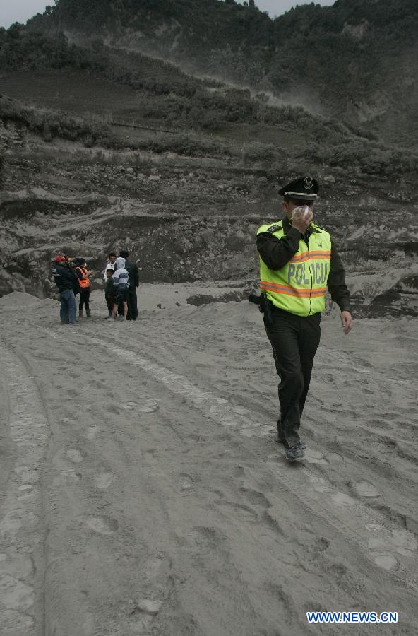 A National Police member uses mask as he walks on a path covered with ashes near the Tungurahua volcano, in the Tungurahua province, Ecuador, on July 14, 2013. The Ecuador's Risk Management Secretariat, declared an orange alert in some locations near the volcano where several families have been evacuated to the shelters prepared for the emergency, according to local press. (Xinhua/Str)