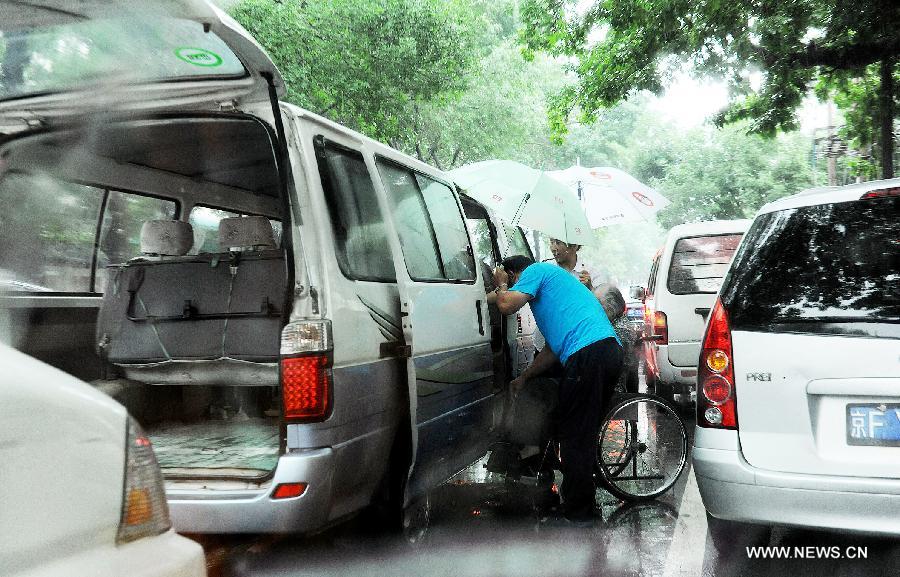 An elder is helped transfer to a hospital in traffic jam in Beijing, capital of China, July 15, 2013. Beijing's meteorologic center on Monday issued a yellow alert for rainstorm, as the lasting rainfall affected Beijing's traffic. (Xinhua/He Junchang) 