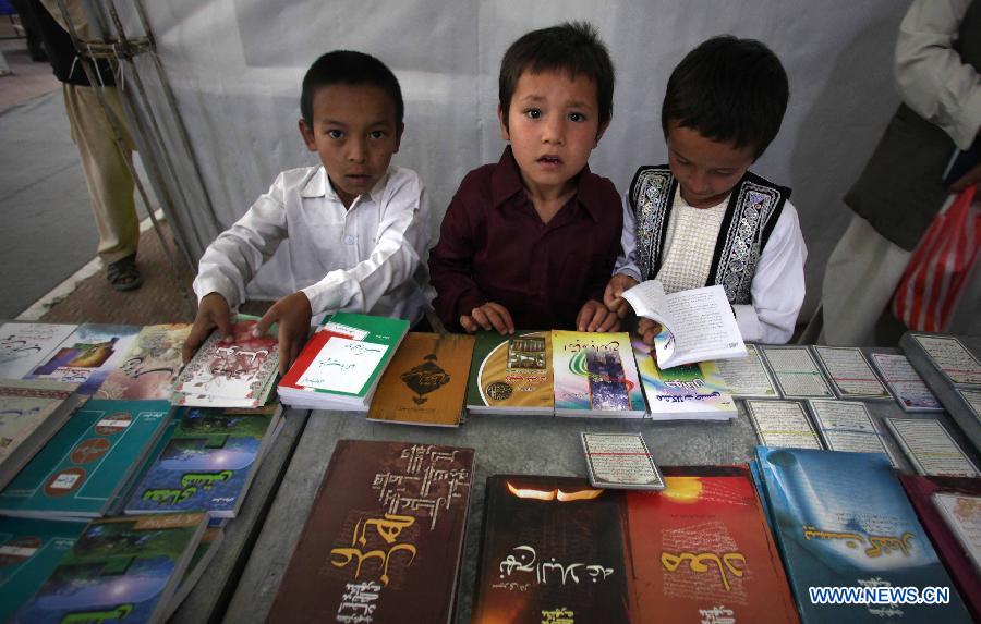 Afghan children stand by a booth at a book exhibition in Kabul, capital of Afghanistan, on July 15, 2013. A 10-day book exhibition kicked off in Kabul to mark the start of Ramadan or Muslim holy month of fasting which began on July 10. (Xinhua/Ahmad Massoud)