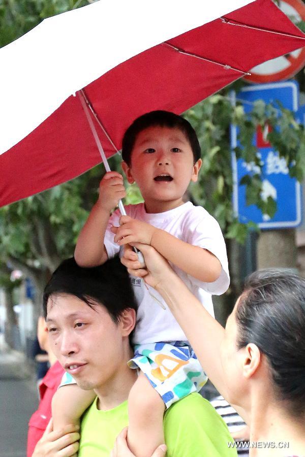 A child holds an umbrella to shade himself from the sun in Shanghai, east China's municipality, July 15, 2013. Local meteorological observatory issued an yellow-coded alert of heat at noon on July 15, 2013.(Xinhua/Yang Shichao)  