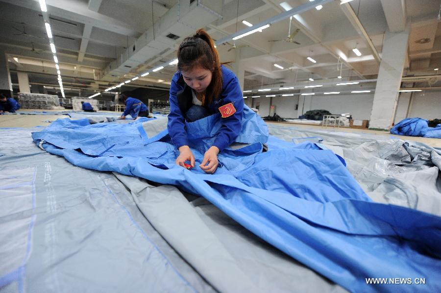 Photo taken on April 22, 2013 shows a quality inspector checking on a tent in a company's factory in Deqing County, east China's Zhejiang Province. China's gross domestic product (GDP) totaled 24.8 trillion yuan (4 trillion U.S. dollars) in the first half of 2013, with the growth at 7.6 percent, which is in line with market expectations and was above the government's full-year target of 7.5 percent, data from China's National Bureau of Statistics (NBS) showed on July 15, 2013. (Xinhua/Ju Huanzong)