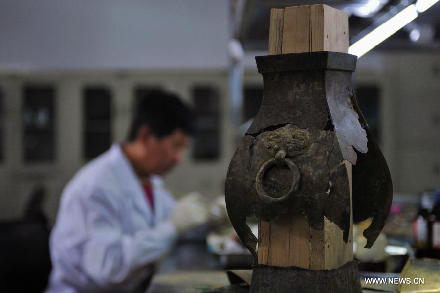 Photo taken on July 15, 2013 shows an ancient bronze ware to be repaired at the relics conservation center of the museum of Tianshui City, northwest China's Gansu Province. A total of six cultural relics preservation experts of the museum conduct the conservation work on relic items here. They use modern technology as well as traditional handicraft to repair and restore cultural relic fragments and damaged bronze wares. (Xinhua/Chen Bin) 